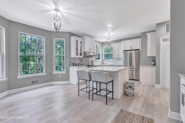 8 Armistead Ky, Colts Neck, NJ 07722 - kitchen featuring freestanding refrigerator, under cabinet range hood, white cabinetry, light countertops, and a kitchen bar