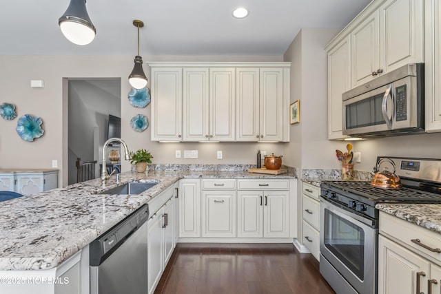 126 Waypoint Dr, Eatontown, NJ 07724 - kitchen featuring stainless steel appliances, a peninsula, dark wood-style flooring, light stone countertops, and decorative light fixtures