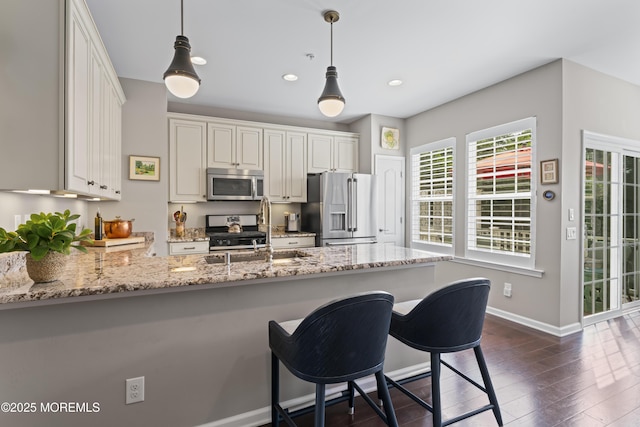 126 Waypoint Dr, Eatontown, NJ 07724 - kitchen featuring stainless steel appliances, a peninsula, light stone countertops, a kitchen breakfast bar, and decorative light fixtures