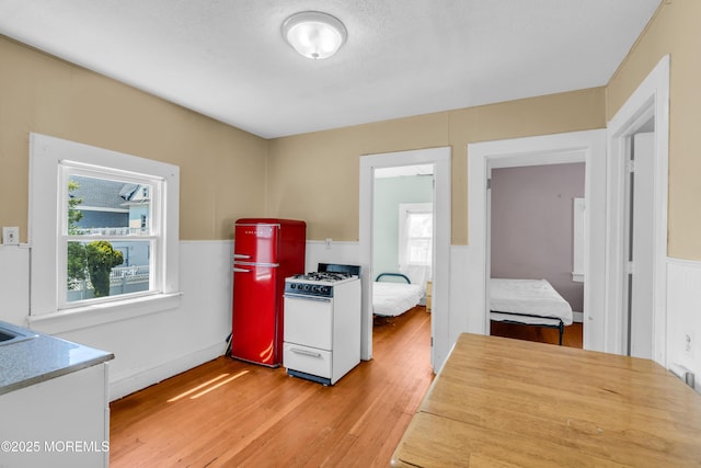 1103 A St, Belmar, NJ 07719 - kitchen with white gas stove, freestanding refrigerator, a wainscoted wall, light wood finished floors, and healthy amount of natural light