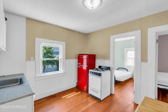 1103 A St, Belmar, NJ 07719 - kitchen featuring white gas stove, a wainscoted wall, freestanding refrigerator, light wood-style flooring, and light countertops