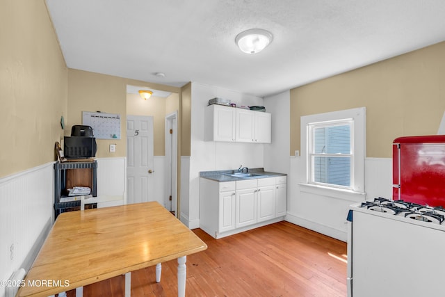 1103 A St, Belmar, NJ 07719 - kitchen featuring white gas range oven, light wood-type flooring, white cabinets, and wainscoting