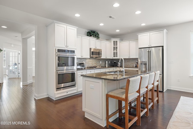 11 Starboard Ct, Little Egg Harbor, NJ 08087 - kitchen featuring stainless steel appliances, tasteful backsplash, a center island with sink, dark stone countertops, and glass insert cabinets