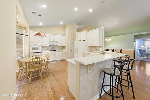 105 Golf View Dr, Little Egg Harbor, NJ 08087 - kitchen with white appliances, a kitchen breakfast bar, light wood finished floors, lofted ceiling, and a peninsula