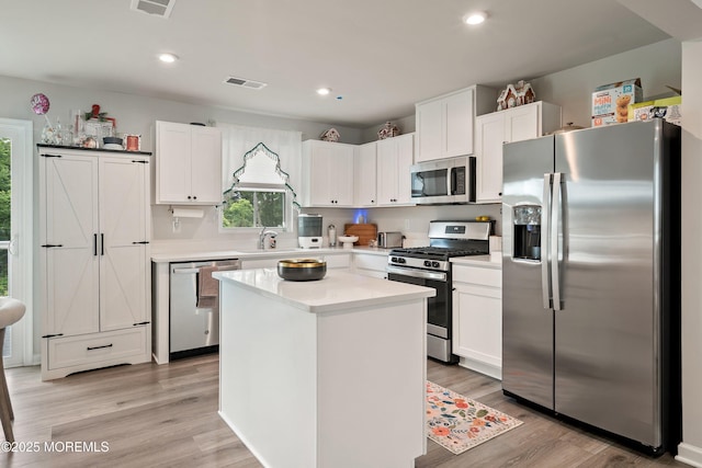 404 Cyprus Ct, Forked River, NJ 08731 - kitchen featuring stainless steel appliances, white cabinets, light countertops, light wood-style flooring, and a center island