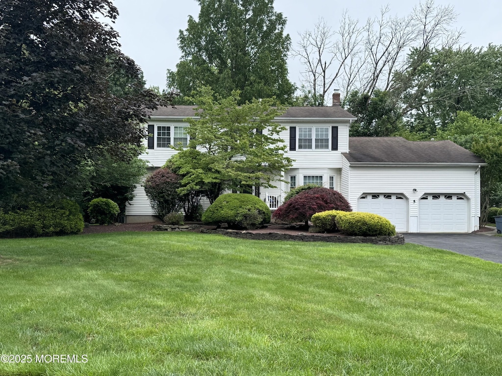 5 Foxboro Ln, Manalapan, NJ 07726 - view of front of home featuring an attached garage, a chimney, driveway, and a front lawn