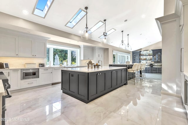 139 Stone Hill Rd, Colts Neck, NJ 07722 - kitchen featuring a skylight, light countertops, a kitchen island, white cabinets, and vaulted ceiling