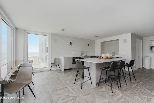 675 Ocean Ave Unit 5J, Long Branch, NJ 07740 - kitchen featuring light countertops, a breakfast bar, a center island, modern cabinets, and decorative backsplash