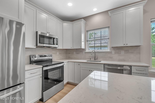 31 Orleans Dr, Manchester, NJ 08759 - kitchen with stainless steel appliances, light stone countertops, white cabinetry, decorative backsplash, and light wood-type flooring