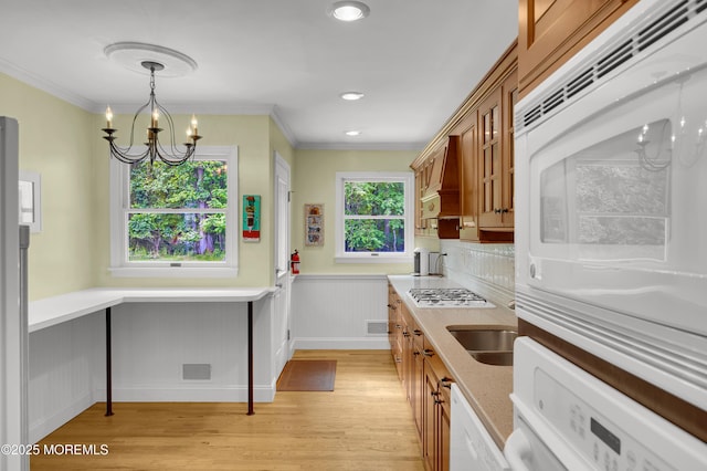4607 Broad St, Wall, NJ 07753 - kitchen with light wood finished floors, a chandelier, brown cabinetry, crown molding, and white gas stovetop