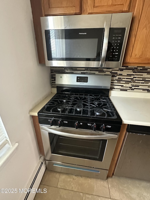 66 Fox Rd Unit 10A, Edison, NJ 08817 - kitchen view of stainless steel appliances, backsplash, brown cabinetry, light countertops, and a baseboard radiator