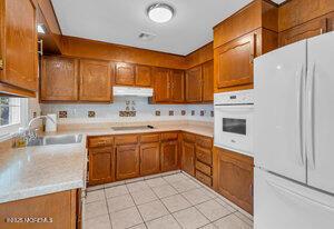 1263 Hamilton Ct Unit B, Lakewood, NJ 08701 - kitchen with white appliances, brown cabinetry, under cabinet range hood, and light countertops