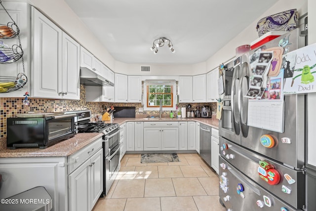 104 Starlight Rd, Howell, NJ 07731 - kitchen with appliances with stainless steel finishes, under cabinet range hood, tasteful backsplash, white cabinetry, and light tile patterned flooring