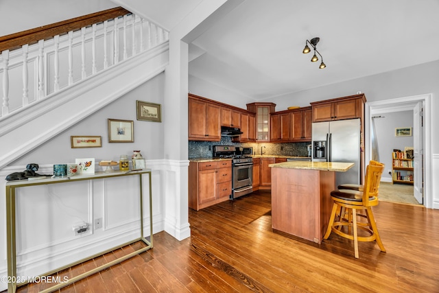 1108 Emory St, Asbury Park, NJ 07712 - kitchen with appliances with stainless steel finishes, brown cabinetry, dark wood finished floors, a kitchen breakfast bar, and wainscoting
