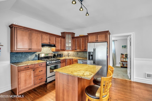 1108 Emory St, Asbury Park, NJ 07712 - kitchen featuring stainless steel appliances, under cabinet range hood, light stone countertops, tasteful backsplash, and dark wood-style flooring