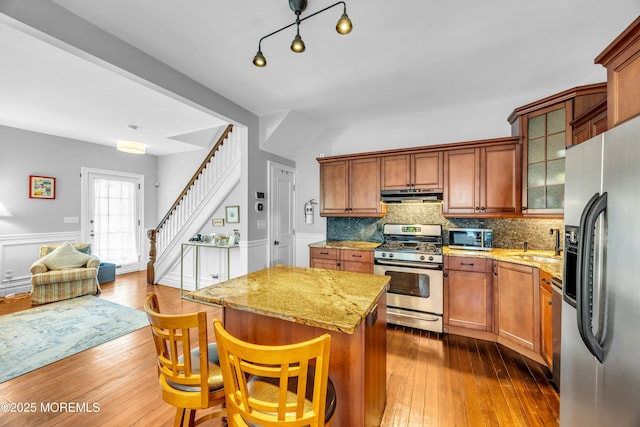 1108 Emory St, Asbury Park, NJ 07712 - kitchen with stainless steel appliances, under cabinet range hood, a center island, light stone counters, and glass insert cabinets