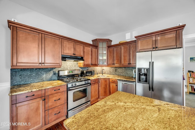 1108 Emory St, Asbury Park, NJ 07712 - kitchen featuring stainless steel appliances, under cabinet range hood, light stone counters, decorative backsplash, and glass insert cabinets