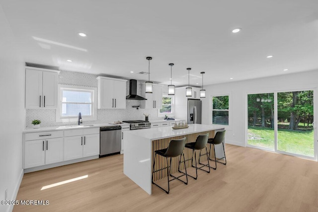 9 Westbrook Dr, Toms River, NJ 08757 - kitchen featuring appliances with stainless steel finishes, wall chimney exhaust hood, light wood-style floors, a kitchen island, and backsplash