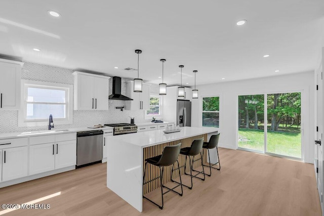9 Westbrook Dr, Toms River, NJ 08757 - kitchen with appliances with stainless steel finishes, wall chimney range hood, tasteful backsplash, light wood-style flooring, and recessed lighting