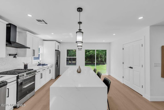 9 Westbrook Dr, Toms River, NJ 08757 - kitchen featuring appliances with stainless steel finishes, wall chimney exhaust hood, a center island, light wood finished floors, and white cabinets