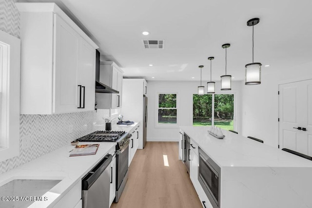 9 Westbrook Dr, Toms River, NJ 08757 - kitchen featuring appliances with stainless steel finishes, wall chimney range hood, white cabinetry, light wood-style flooring, and a spacious island