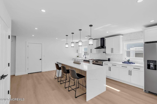 9 Westbrook Dr, Toms River, NJ 08757 - kitchen featuring wall chimney range hood, stainless steel appliances, light wood-style flooring, a kitchen bar, and a kitchen island