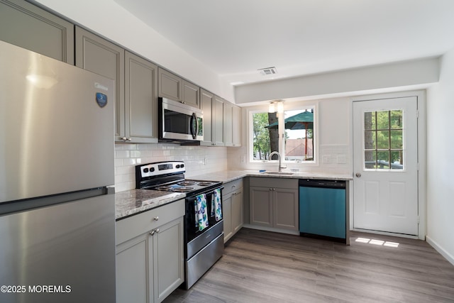 19 Cedar Ave, Manahawkin, NJ 08050 - kitchen with stainless steel appliances, gray cabinetry, tasteful backsplash, light stone countertops, and light wood-style floors
