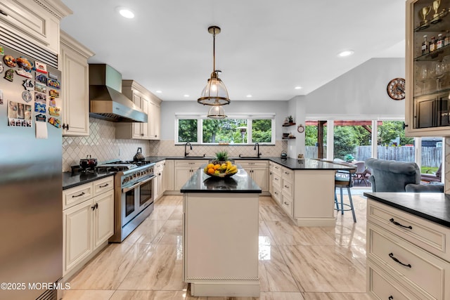 1159 County Line Rd E, Lakewood, NJ 08701 - kitchen with stainless steel appliances, cream cabinetry, wall chimney exhaust hood, dark countertops, and a peninsula