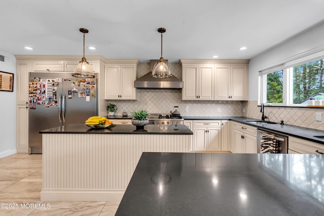 1159 County Line Rd E, Lakewood, NJ 08701 - kitchen featuring cream cabinetry, wall chimney exhaust hood, dark countertops, appliances with stainless steel finishes, and decorative backsplash
