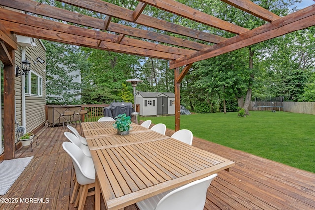 1159 County Line Rd E, Lakewood, NJ 08701 - wooden deck featuring a trampoline, outdoor dining area, a storage unit, and a lawn