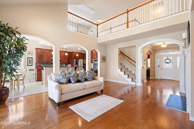 19 E Francesa Ct, Farmingdale, NJ 07727 - living area with arched walkways, a towering ceiling, stairway, and light wood-type flooring