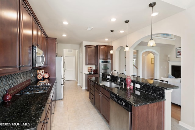 19 E Francesa Ct, Farmingdale, NJ 07727 - kitchen with appliances with stainless steel finishes, arched walkways, decorative backsplash, dark stone counters, and a kitchen island with sink