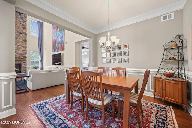 86 Legacy Ct, Freehold, NJ 07728 - dining area featuring ornamental molding, a fireplace, wood finished floors, wainscoting, and a chandelier