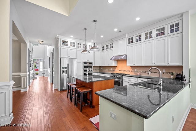 86 Legacy Ct, Freehold, NJ 07728 - kitchen featuring premium appliances, a kitchen bar, dark wood-style flooring, under cabinet range hood, and dark stone counters