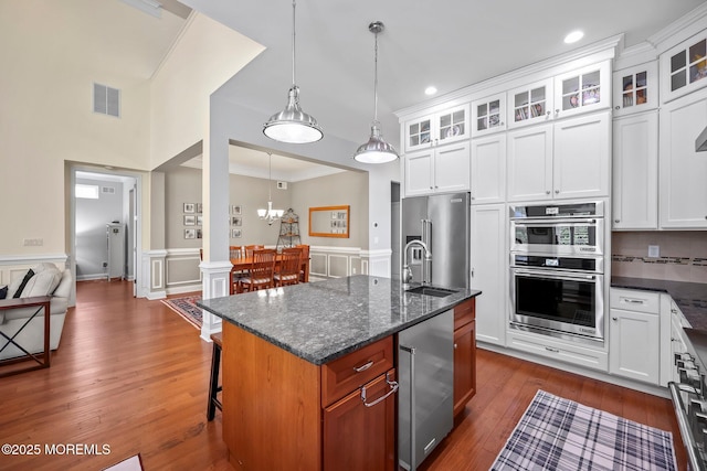 86 Legacy Ct, Freehold, NJ 07728 - kitchen with stainless steel appliances, glass insert cabinets, a kitchen bar, dark stone countertops, and an island with sink