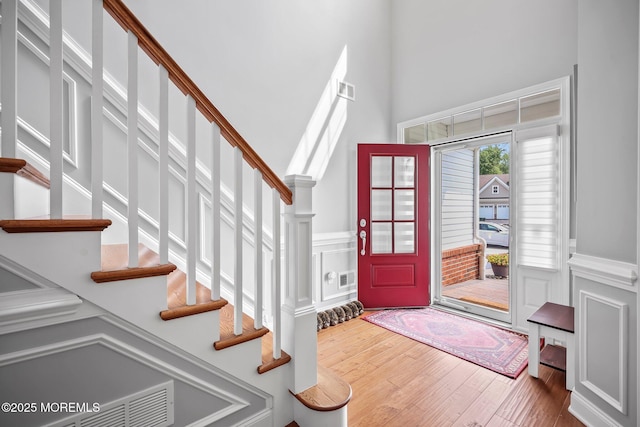 86 Legacy Ct, Freehold, NJ 07728 - entryway featuring wood finished floors, stairs, a high ceiling, wainscoting, and a decorative wall