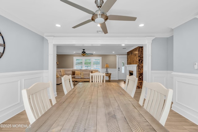 18 Pinewood Dr, Brick, NJ 08724 - dining area featuring a decorative wall, a ceiling fan, wainscoting, a warm lit fireplace, and crown molding