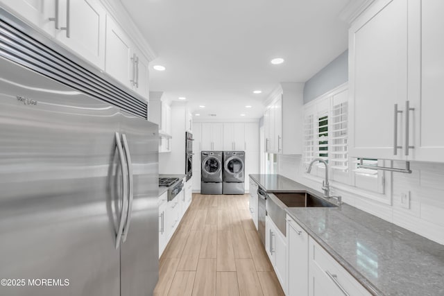18 Pinewood Dr, Brick, NJ 08724 - kitchen featuring stainless steel appliances, washing machine and clothes dryer, white cabinetry, decorative backsplash, and dark stone countertops