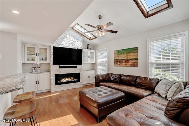 46 Sweet Gum Rd, Howell, NJ 07731 - living room featuring a skylight, lofted ceiling, ceiling fan, light wood-style flooring, and a stone fireplace