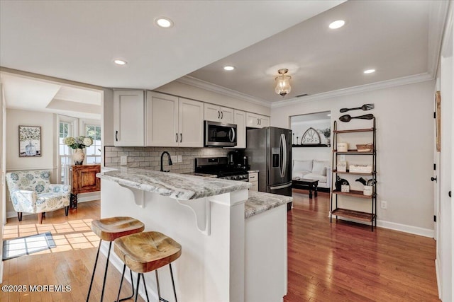 46 Sweet Gum Rd, Howell, NJ 07731 - kitchen featuring stainless steel appliances, a kitchen breakfast bar, light wood-style floors, light stone countertops, and backsplash