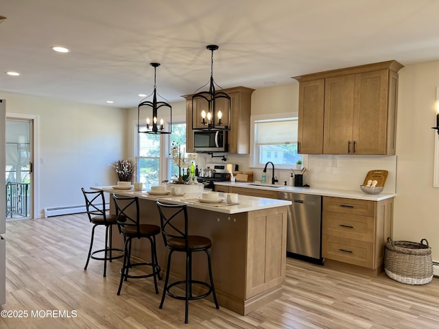 31 Guadeloupe Dr, Toms River, NJ 08757 - kitchen with stainless steel appliances, a chandelier, baseboard heating, light wood-type flooring, and decorative backsplash