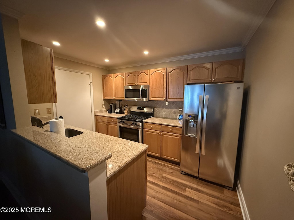 455 Deuce Dr, Wall, NJ 07719 - kitchen featuring stainless steel appliances, ornamental molding, light wood-type flooring, backsplash, and a peninsula