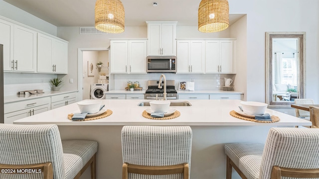 10 Victoria Gardens Sq, Neptune Township, NJ 07753 - kitchen with appliances with stainless steel finishes, washer / dryer, tasteful backsplash, and an island with sink