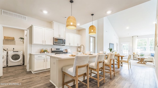 14 Victoria Gardens Sq, Neptune Township, NJ 07753 - kitchen featuring stainless steel appliances, washer and dryer, wood finished floors, an island with sink, and backsplash