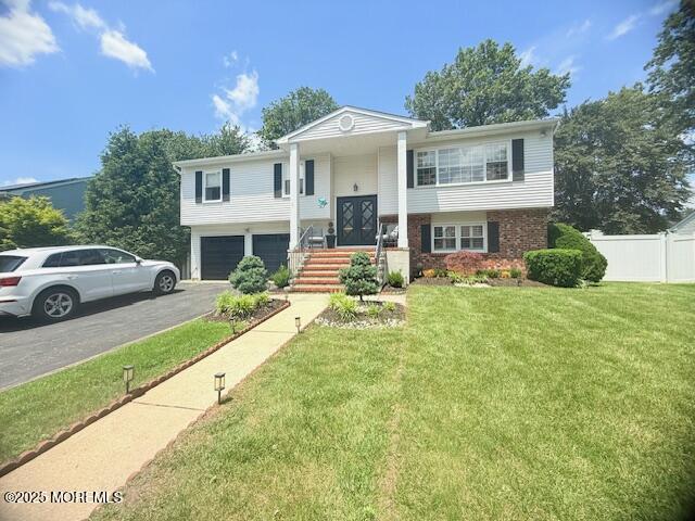 11 Bristlecone Dr, Howell, NJ 07731 - bi-level home featuring asphalt driveway, an attached garage, and brick siding