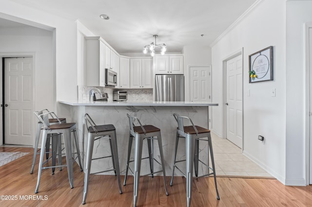 22 Cooper Ave Unit 113, Long Branch, NJ 07740 - kitchen featuring appliances with stainless steel finishes, a peninsula, light countertops, a kitchen bar, and backsplash