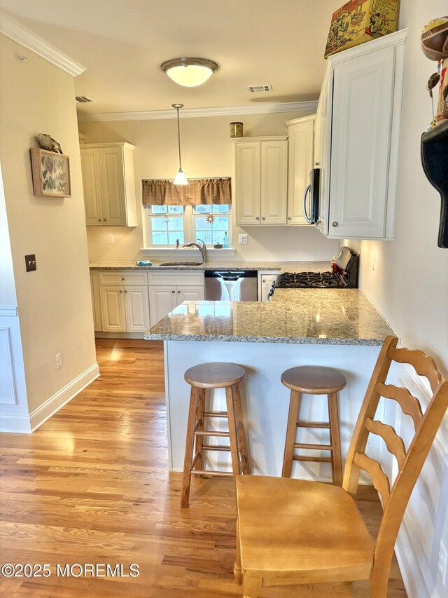 119 Dupont Ave Unit 10, Seaside Heights, NJ 08751 - kitchen featuring appliances with stainless steel finishes, a peninsula, a kitchen bar, light wood-style flooring, and ornamental molding