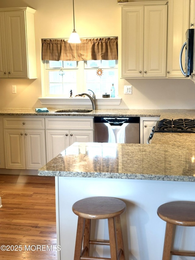 119 Dupont Ave Unit 10, Seaside Heights, NJ 08751 - kitchen featuring stainless steel appliances, a kitchen bar, white cabinets, and light wood finished floors
