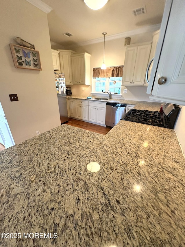 119 Dupont Ave Unit 10, Seaside Heights, NJ 08751 - kitchen with appliances with stainless steel finishes, light stone countertops, ornamental molding, white cabinetry, and light wood-style flooring