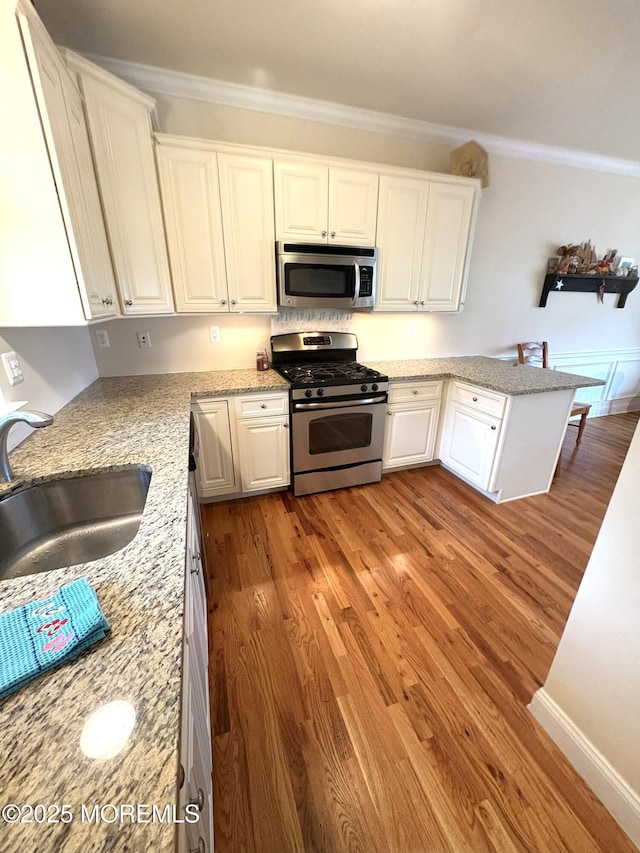 119 Dupont Ave Unit 10, Seaside Heights, NJ 08751 - kitchen featuring stainless steel appliances, crown molding, light wood-type flooring, white cabinetry, and light stone counters